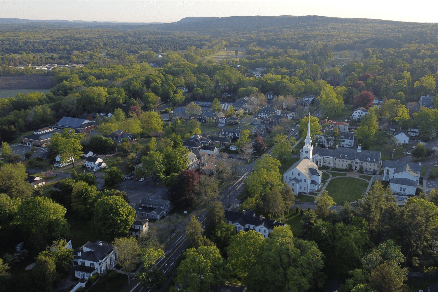 Aerial drone view of Farmington, CT showcasing tree-lined streets, residential homes, and scenic landscapes.